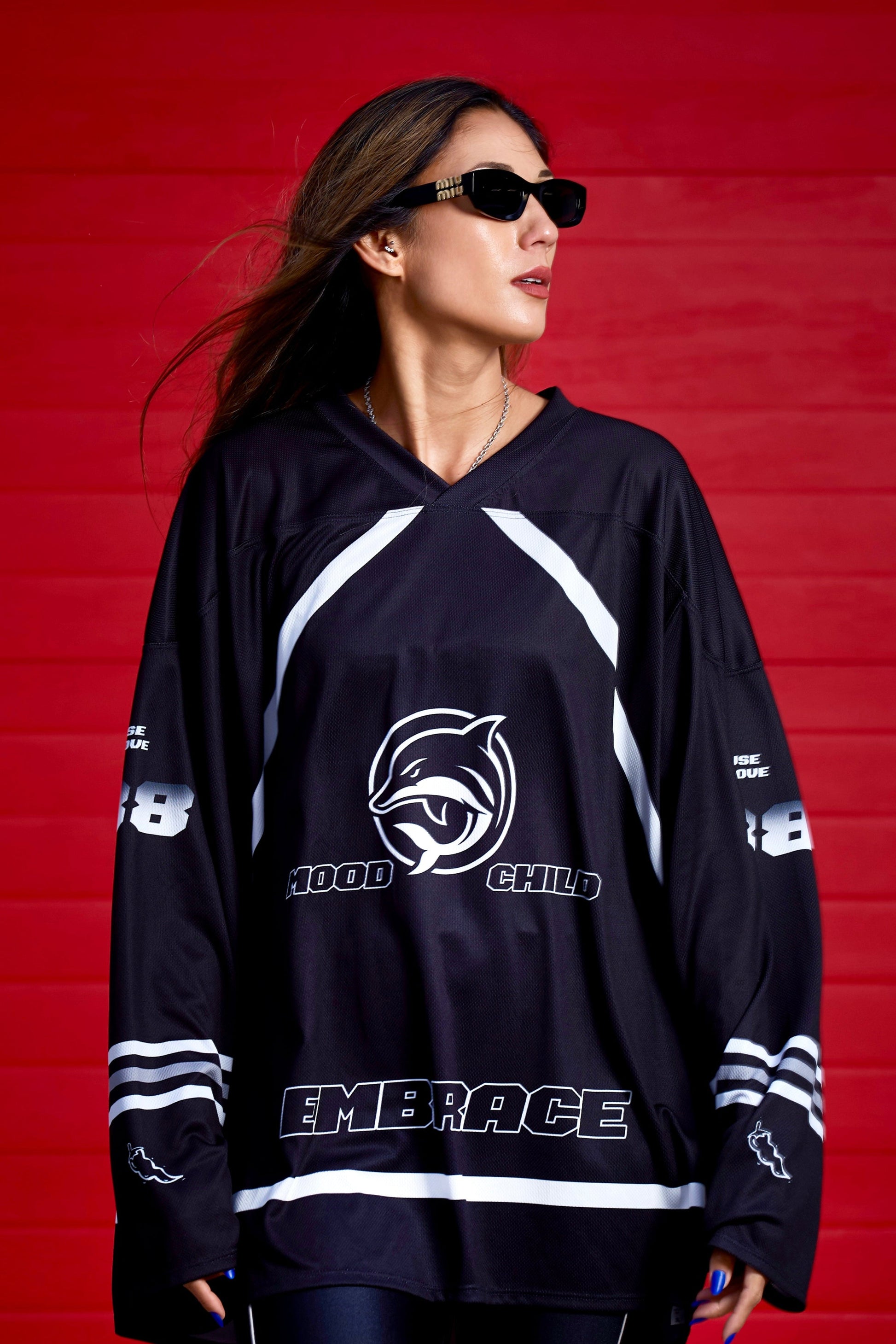 Manda Moor wearing Mood Child Mighty Daulphin black sports jersey with white text and logos against a red background